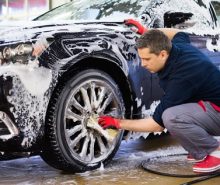 hombre lavando las llantas de un coche en un car wash